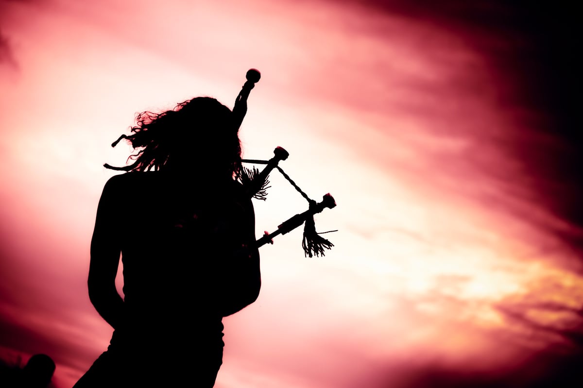 Silhouette of a man playing the bagpipe at dusk