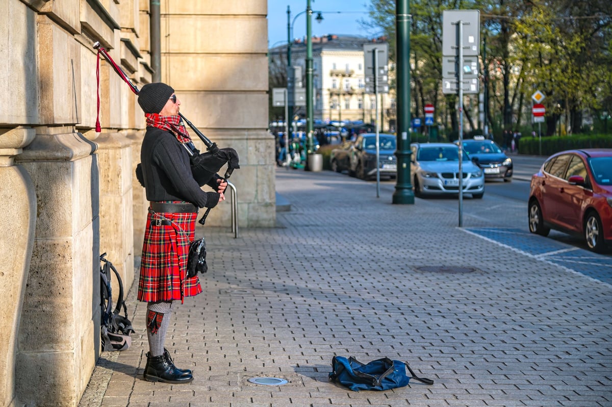 Man in a kilt playing the bagpipe on a city street