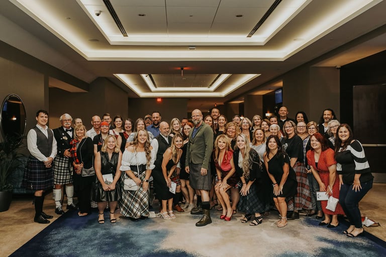 Large group of people in formal attire posing together in an elegant indoor venue with modern lighting